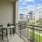  A balcony with a table and chairs overlooks a street with apartment buildings.