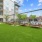  A large grassy area in front of a building with a metal fence and benches.