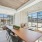  A long wooden table is surrounded by chairs in a room with a view of the outside.