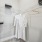  A white robe is hanging on a hanger in a closet.