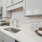  A modern kitchen with a white countertop and a stainless steel sink.