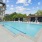  A large outdoor swimming pool with a building in the background.
