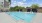  A large outdoor swimming pool with a building in the background.